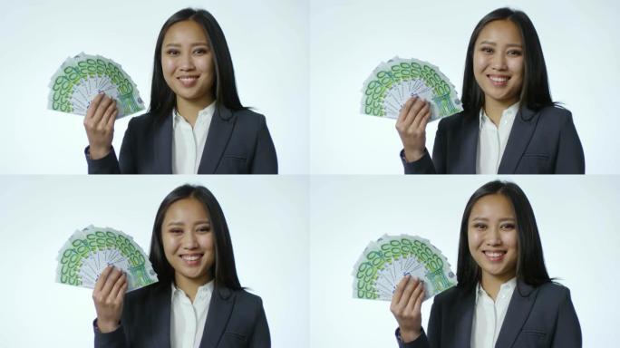 微笑的亚洲女商人与白色背景上的欧元钞票粉丝合影