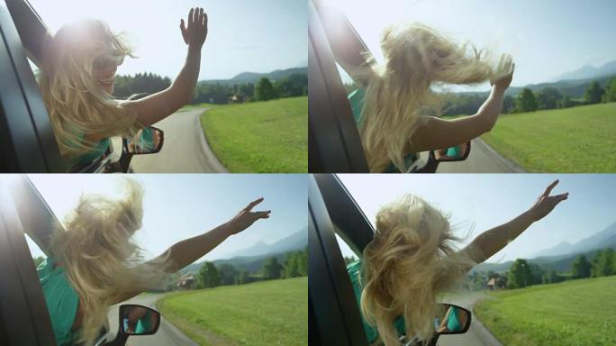 慢动作: 年轻的金发女子在开车时在空中挥舞手臂。