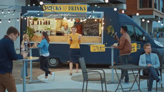 Food Truck员工向快乐的年轻时髦顾客提供新鲜制作的牛肉汉堡，薯条和冷饮。在现代凉爽的街区出售