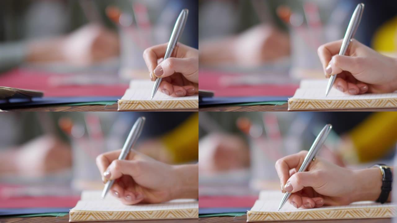 年轻女子在笔记本上写字的手