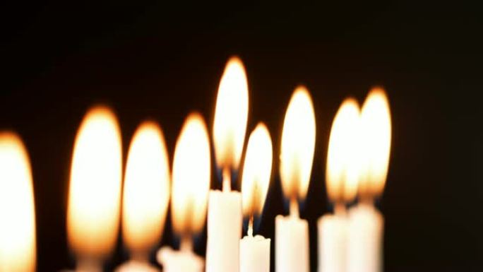 在光明节犹太节日燃烧的一排九支白色蜡烛上燃烧的火焰的详细照片