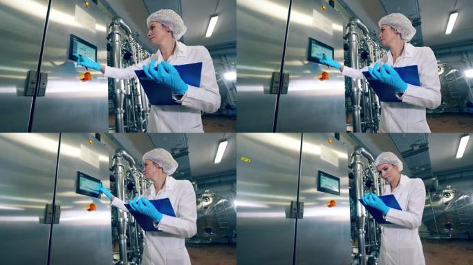 工厂工人检查一台机器，在显示器上打字。女工控制生产设备的质量。