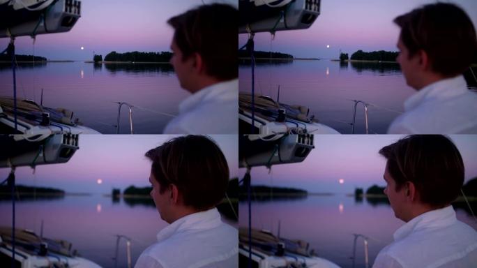 湖上浪漫的日落。年轻人从船上看风景