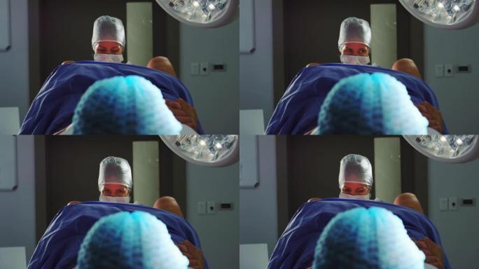 高加索女性外科医生在手术室分娩时检查孕妇的前视图