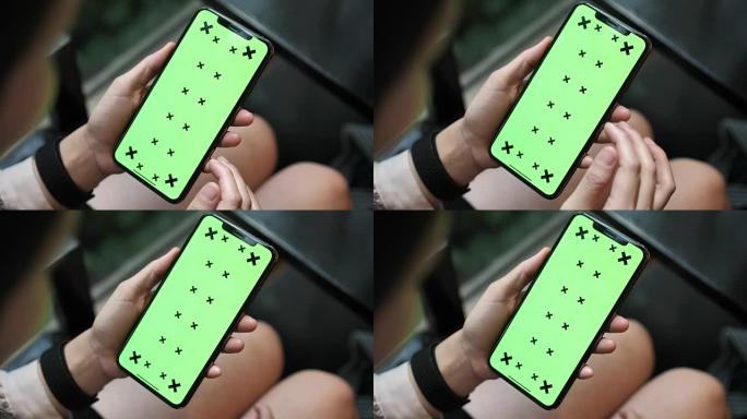 手拿绿屏显示的女人触摸智能手机