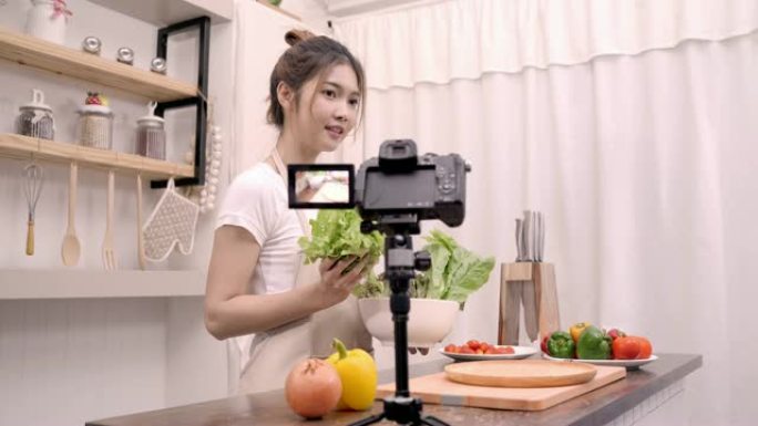 博主亚洲妇女使用相机记录如何制作沙拉健康的食物视频为她的订户，女性使用有机蔬菜准备沙拉适合身体在家里