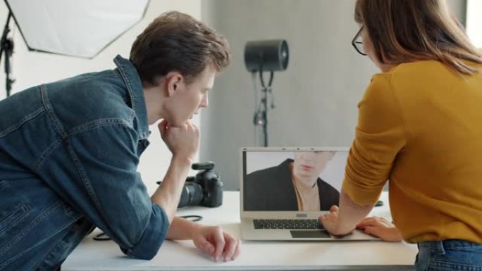 在摄影工作室的笔记本电脑屏幕上观看照片的女孩和男孩的后视图