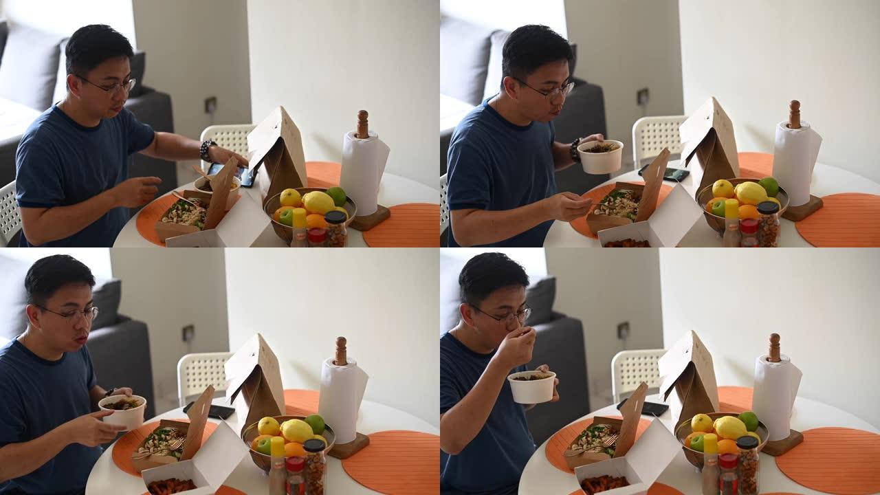 一名亚洲华人中年男子用手机拍下他点的外卖放在餐桌上