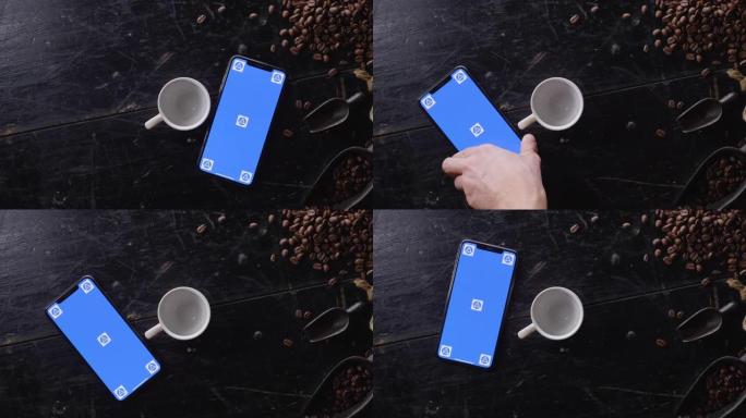 带咖啡豆的木制桌子上的蓝屏智能手机