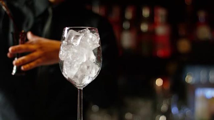 在夜总会或酒吧里，专业调酒师准备一杯加冰酒的鸡尾酒。酒保测量完美鸡尾酒的数量。概念: 迪斯科，乐趣，