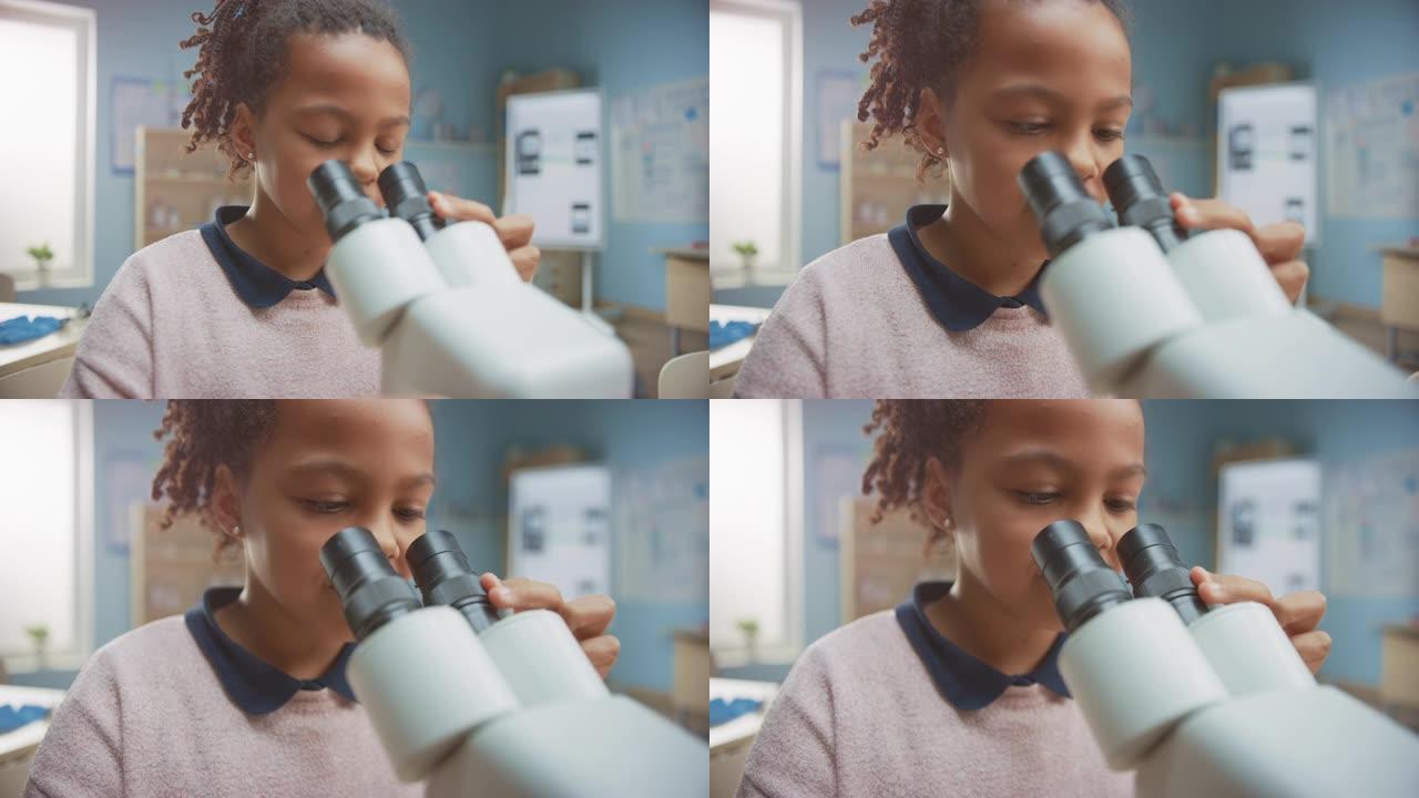 聪明的小女孩在显微镜下看的肖像。在小学教室里，可爱的女孩使用显微镜。STEM (科学、技术、工程和数