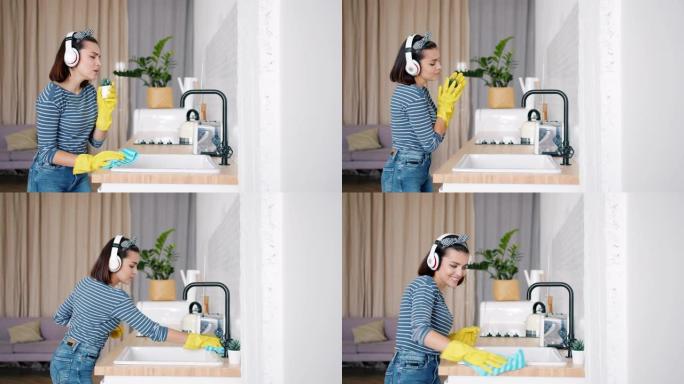 快乐的女孩戴着耳机在厨房打扫时在室内植物里唱歌