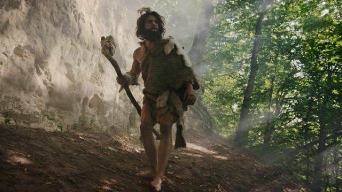戴着动物皮的原始穴居人手持石尖锤从洞穴中出来，环顾四周，探索史前森林，准备猎杀动物猎物。尼安德特人进