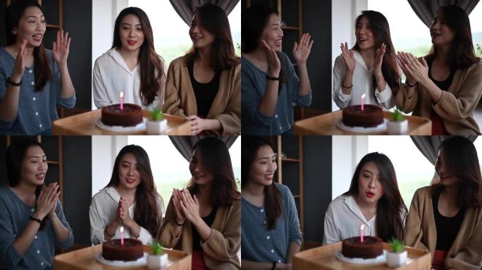 一位亚洲华裔年轻美女在她的公寓里和朋友一起庆祝生日蛋糕