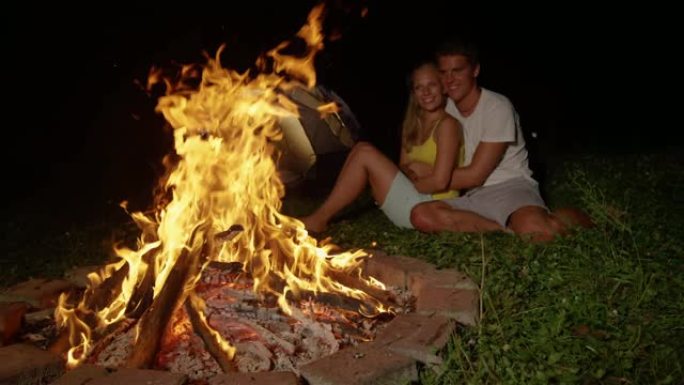 慢动作: 快乐的男人在篝火旁拥抱时亲吻女友的脸颊