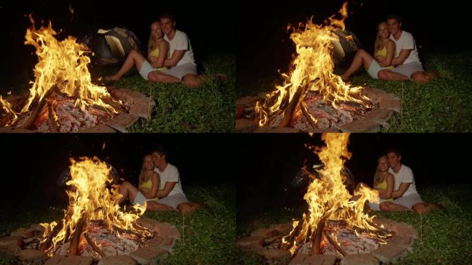 慢动作: 快乐的男人在篝火旁拥抱时亲吻女友的脸颊