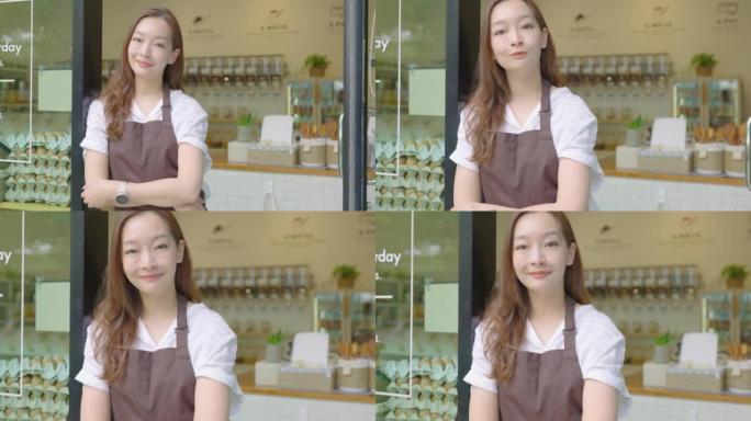 微笑的肖像美丽的亚洲年轻女子，36岁，穿着棕色围裙站在她的可持续零废物杂货店的入口处。成功的小企业主