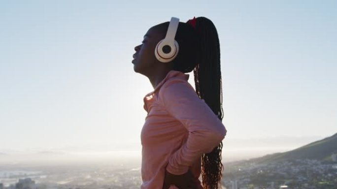 日落时分，在户外锻炼的非裔美国妇女在乡村戴上无线耳机