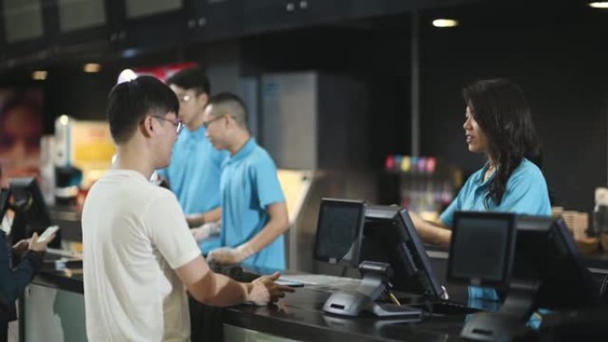 亚洲华人男顾客从电影院电影院售票处购买电影票