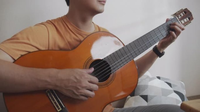 特写镜头亚洲男性通过互联网上的视频通话与他的朋友一起弹吉他电话会议。玩古典吉他的人很开心。音乐家男子