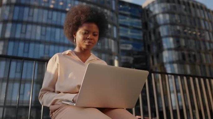 一位皮肤黝黑的年轻女商人在她的笔记本电脑上对着商务中心输入一封电子邮件