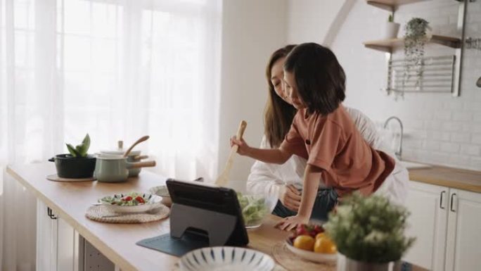 母亲抱着女儿在厨房做饭