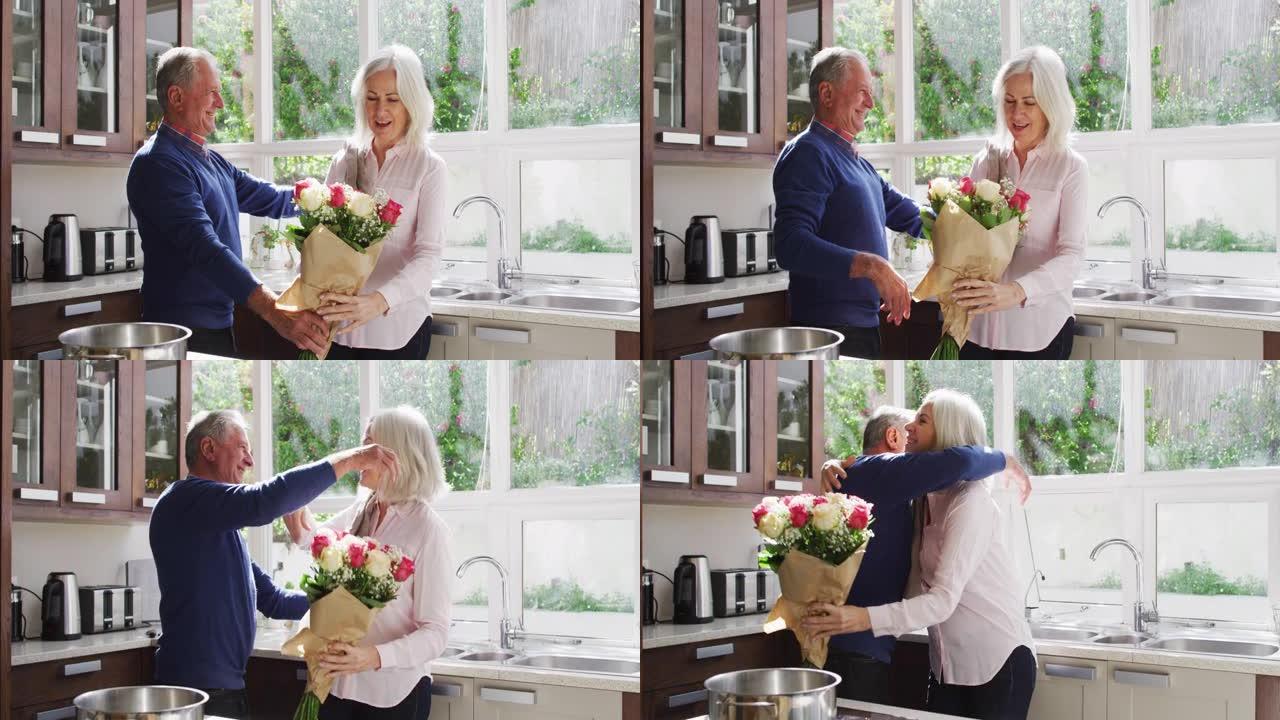 高级男子给妻子一束鲜花，并在家里的厨房里拥抱她