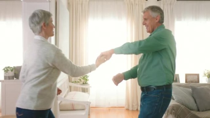 退休和高级夫妇随着音乐跳舞，一起在家庭客厅庆祝信任、浪漫的爱和关怀。退休老年舞者男女快乐地跳舞，带着