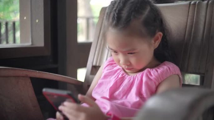 可爱的小女孩用智能手机在长凳上放松