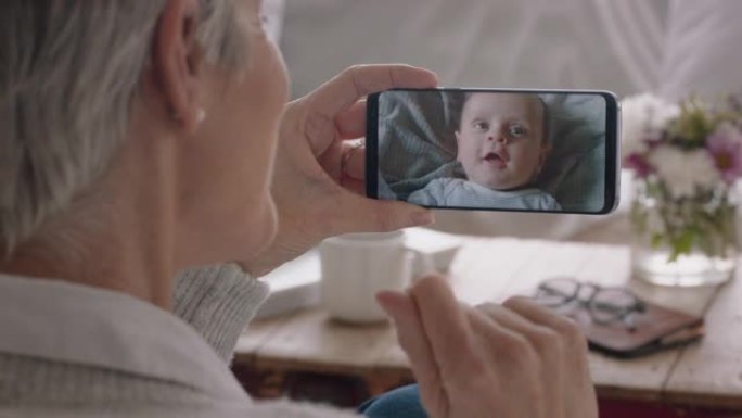 成熟的女人使用智能手机进行视频聊天祖母向婴儿挥手，享受在手机屏幕上与孙子聊天4k镜头