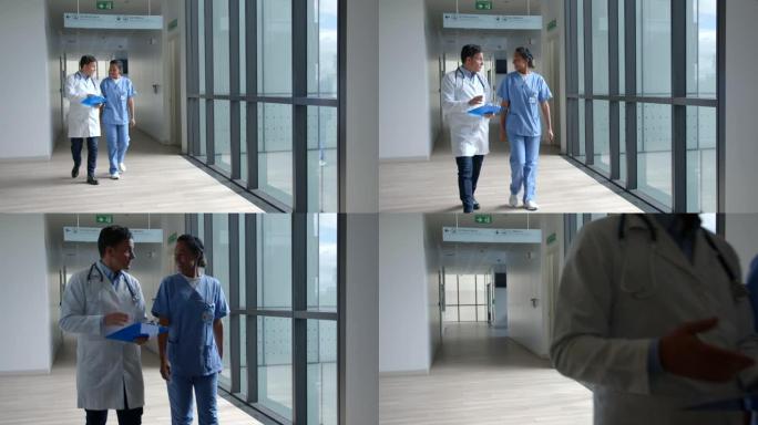 男医生与黑人女护士交谈，同时看着医疗图表并走在医院的走廊上