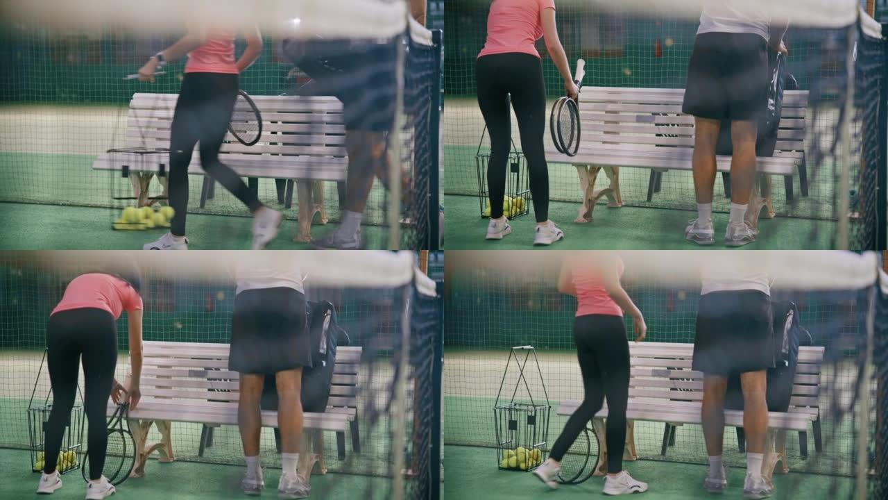 年轻的男教练和妇女将网球设备放在室内网球场上