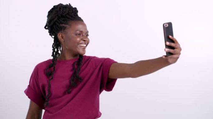 4k视频片段，一位迷人的年轻女子站在粉红色的背景下，用手机自拍