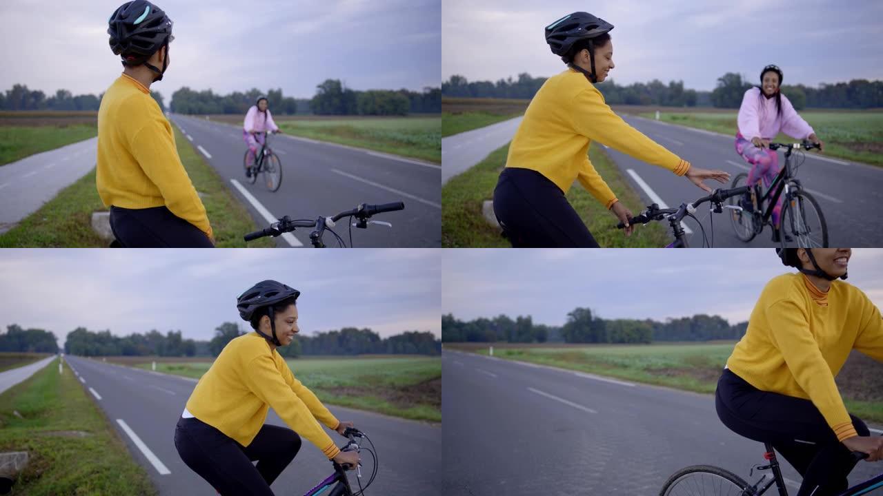 成年女性在高速公路上骑自行车的慢动作镜头，她的伴侣在交换波浪后加入了