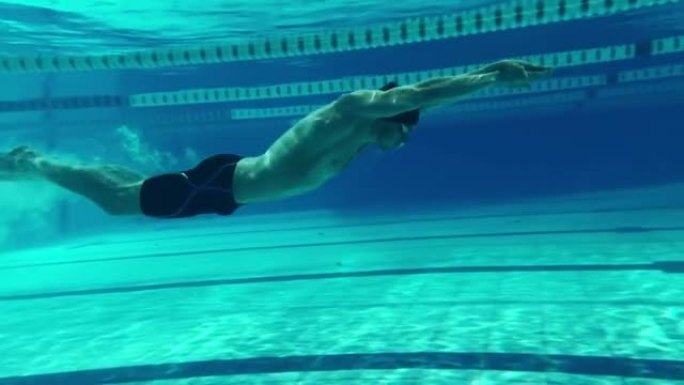 水下射击: 适合肌肉发达的游泳者跳，潜入游泳池。英俊的职业运动员以极快的速度游泳-准备创造世界冠军纪