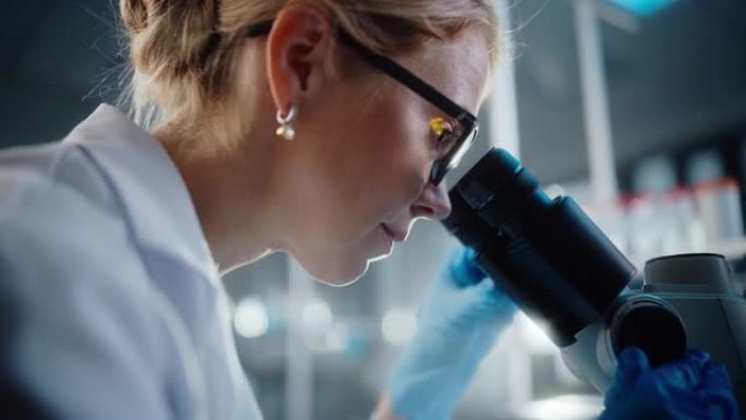 在明亮的医学科学实验室: 美丽的微生物学家戴着眼镜在显微镜下观察分析样品。才华横溢的科学家，与高科技