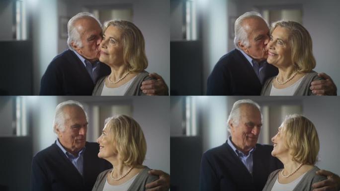 可爱的幸福成熟夫妇的电影镜头正在享受拥抱和亲吻的时光，这是家里客厅里永恒爱情的标志。概念: 爱情，家