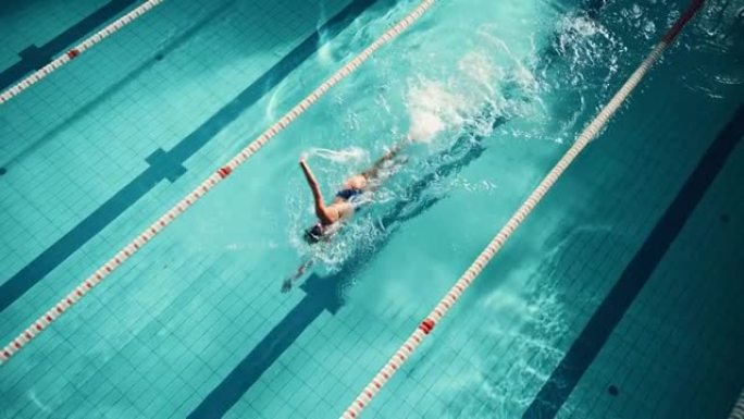 空中俯视图: 游泳池中的竞技女游泳运动员。专业运动员以自由式游泳，决心在训练中赢得冠军。电影慢动作，