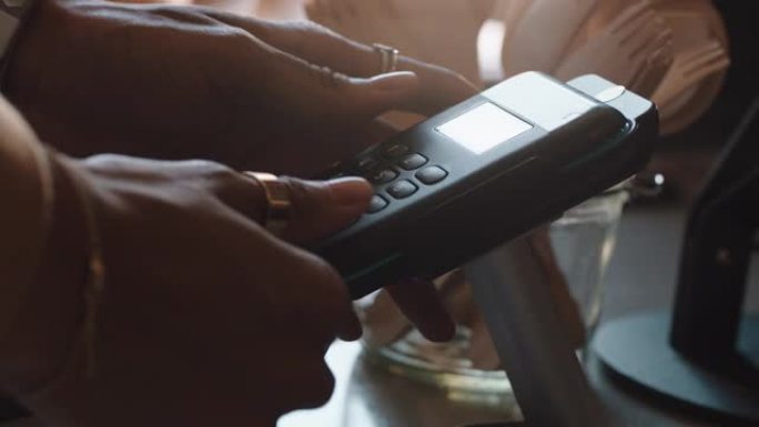 近距离使用信用卡机输入密码客户在咖啡馆付款