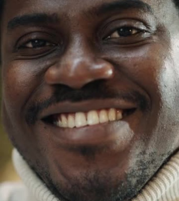 垂直镜头: 一个黑人年轻人的肖像，笑容灿烂，抬头看着相机。特写一位男性非裔美国初创公司创始人的脸，对