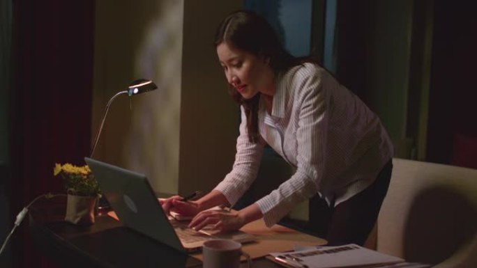 女商人晚上工作她正忙着寻找文件。用电脑笔记本工作。