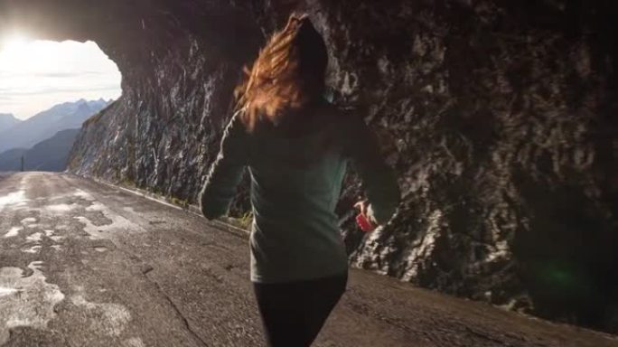 以健康为导向的妇女在山上高高的岩石隧道中奔跑