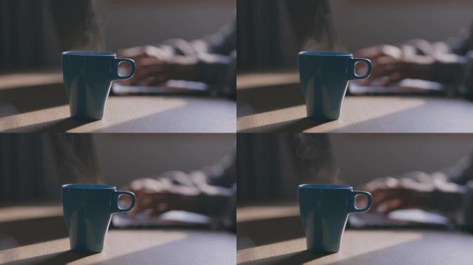 桌上的咖啡杯，双手在笔记本电脑上打字