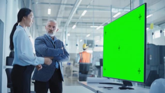 工厂办公室会议: 总工程师在带有绿屏模拟显示的电视的会议室中与业务合作伙伴交谈。重工业和制造业相关模