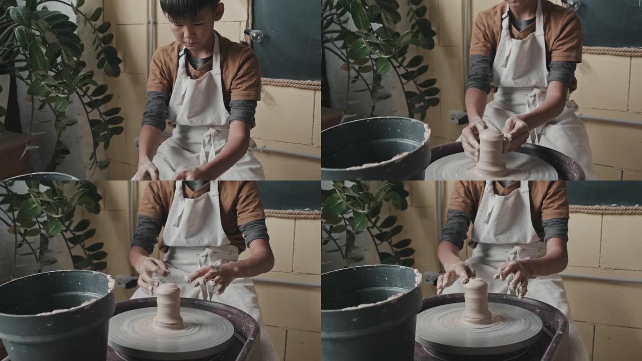 亚洲男孩使用陶轮手工业手艺活特写展示