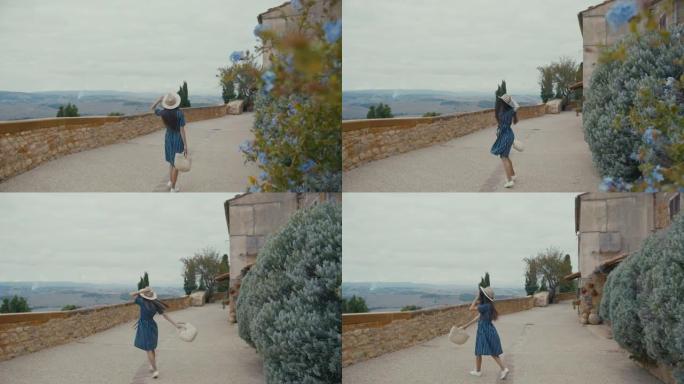 SLO MO女游客在Pienza的城墙边散步时高兴地旋转