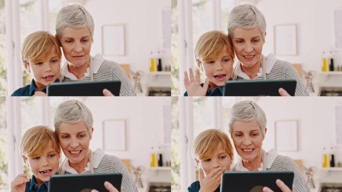 祖母，孩子和平板电脑在视频通话中挥舞，吹吻或在家里虚拟问候。奶奶和小男孩坐在一起，拿着触摸屏在网上打