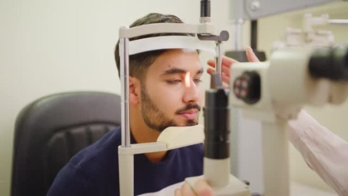 验光师在一名接受眼科检查的年轻人中检测青光眼和眼球后部疾病。在医院眼科诊所咨询患者的检眼镜机器上进行