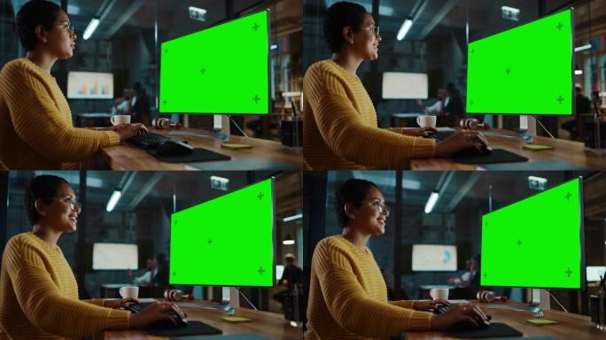 年轻的多民族专家在创意办公室的台式电脑上工作，绿屏模拟显示。美丽多样的短发和眼镜女经理穿着黄色套头衫