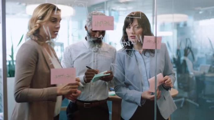 使用便签的商务人士集思广益团队领导女性与同事一起在玻璃白板上写作，在办公室会议上展示解决问题的策略